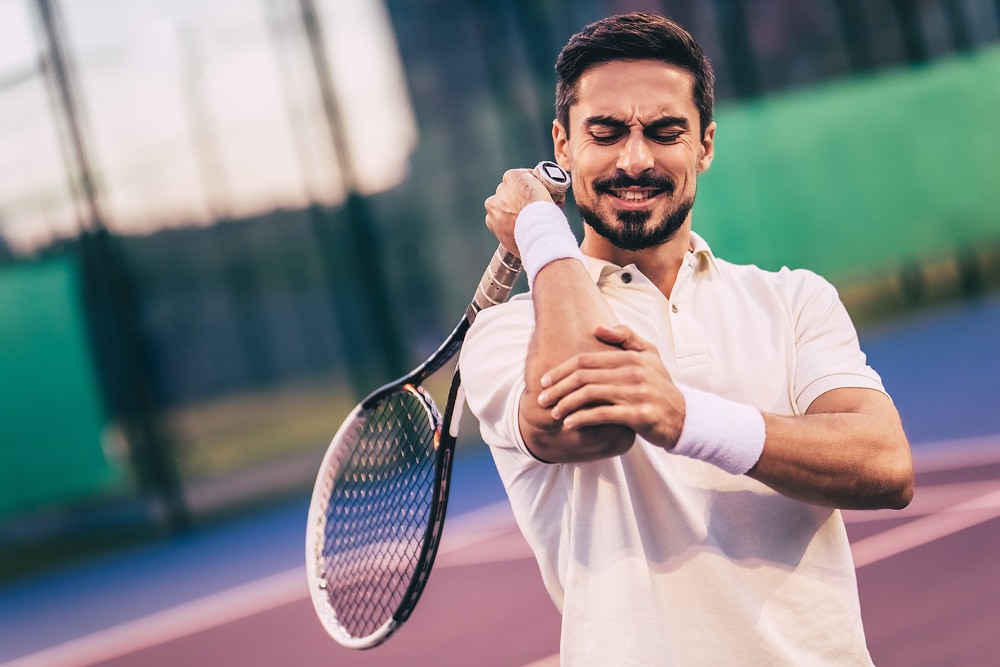 Tennis player holding elbow in pain
